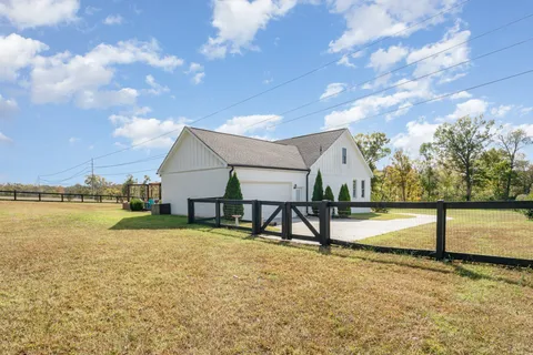 a view of a white house next to a yard with potted plants