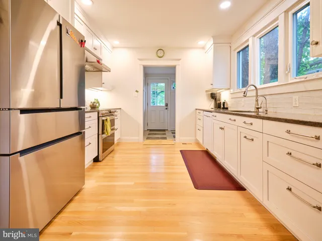 a large white kitchen with stainless steel appliances granite countertop a refrigerator and a sink