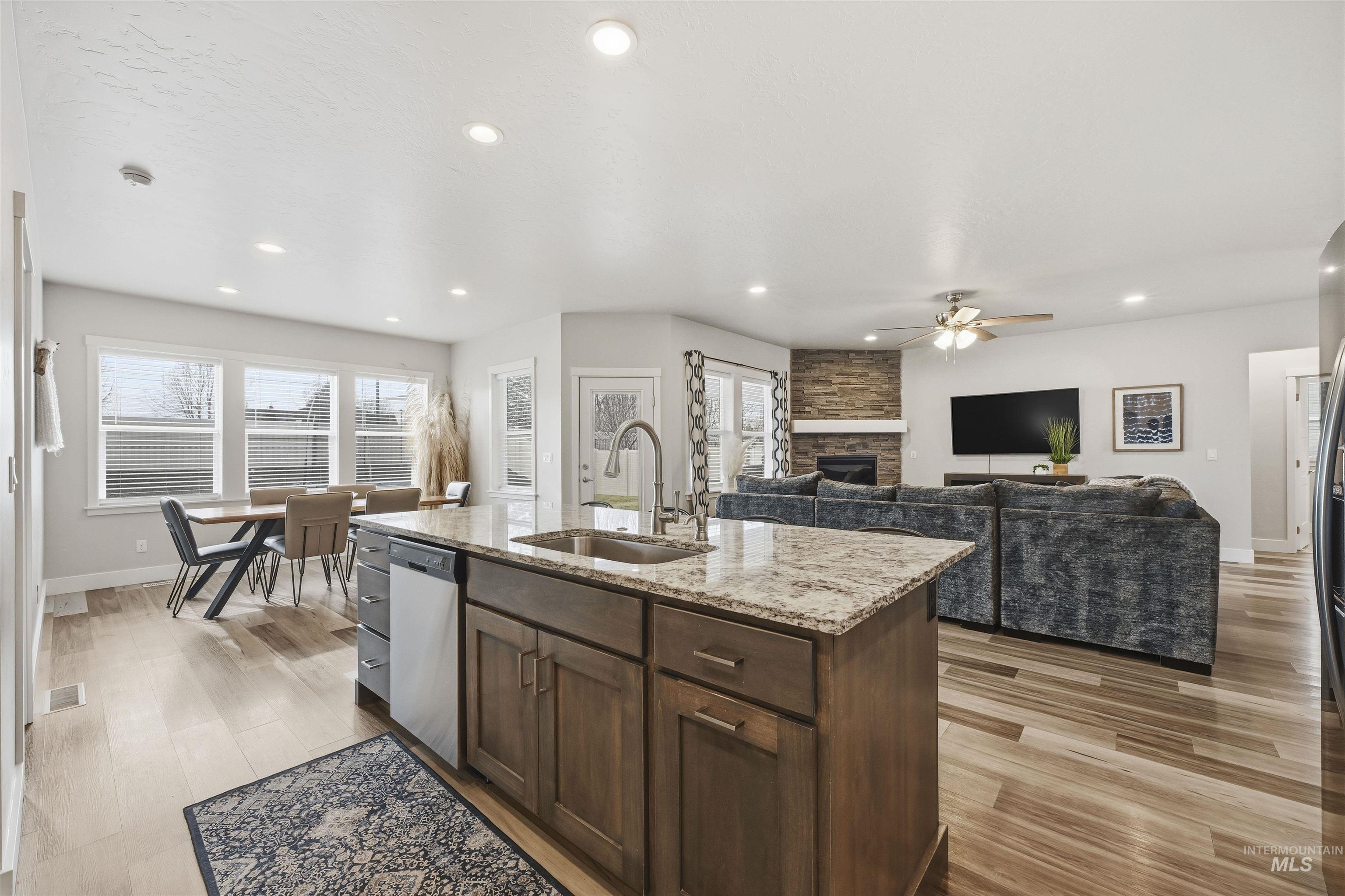 2229 East Grayson Street Meridian, ID 83642 - Photo 40 of 40 Kitchen with light stone counters, dark brown cabinets, a stone fireplace, light wood-type flooring, and open floor plan