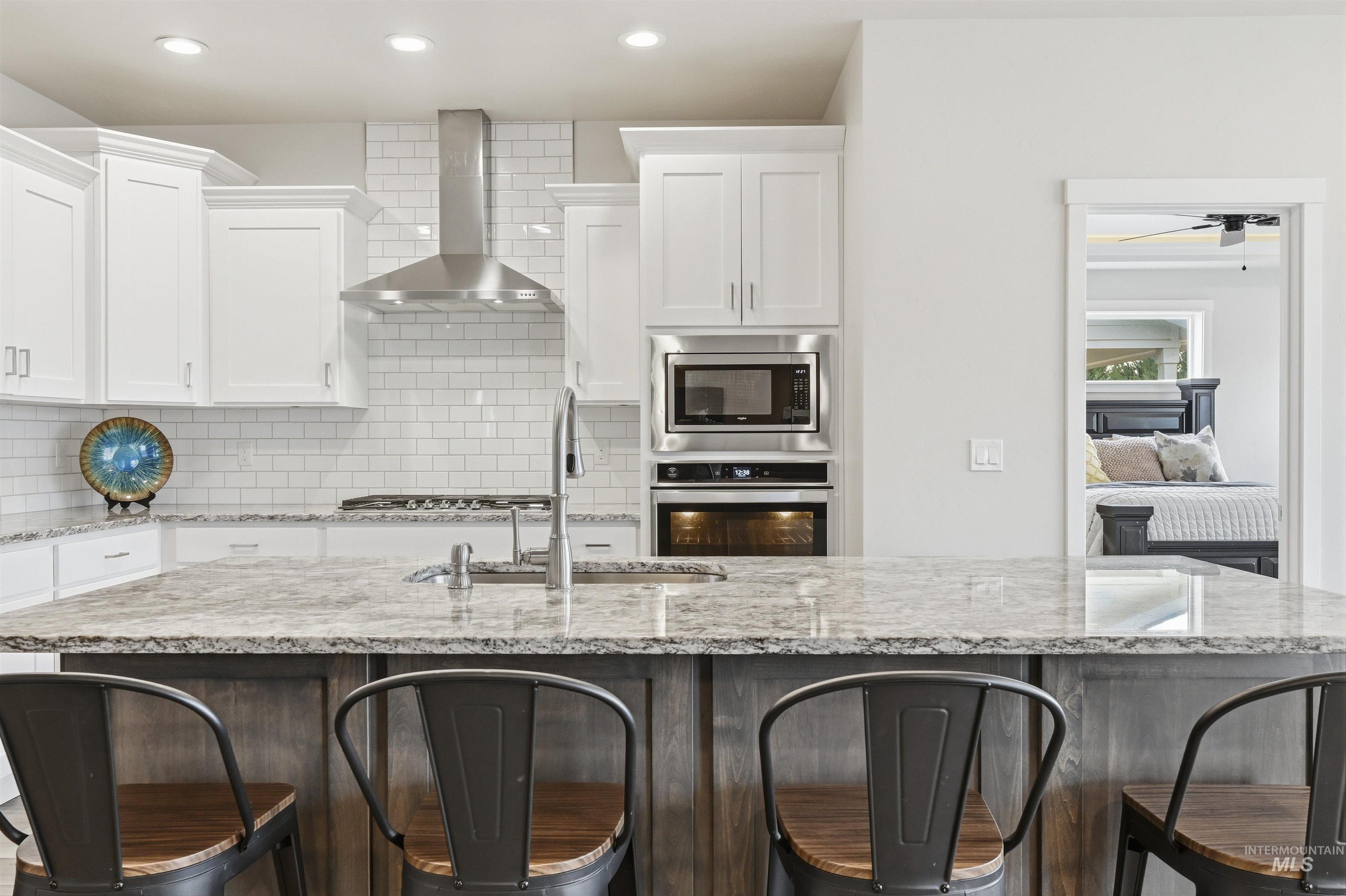 2229 East Grayson Street Meridian, ID 83642 - Photo 11 of 40 Kitchen with a breakfast bar, light stone counters, wall chimney exhaust hood, and recessed lighting