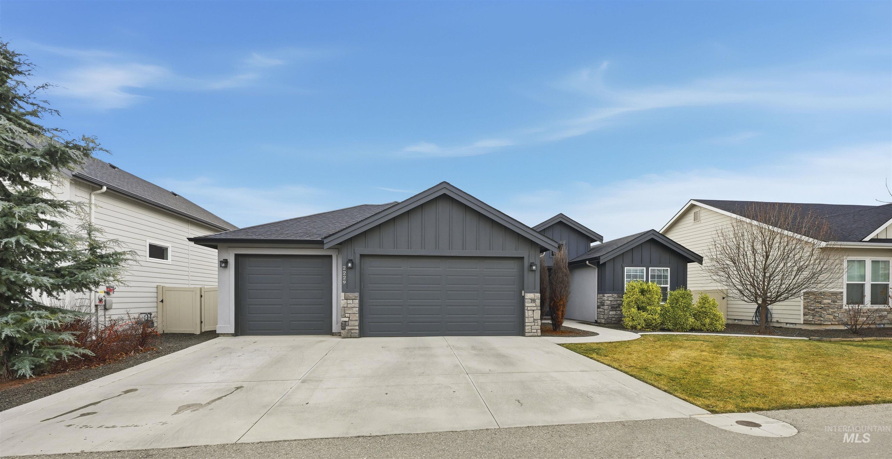 2229 East Grayson Street Meridian, ID 83642 - Photo 3 of 40 View of front of home featuring board and batten siding, stone siding, concrete driveway, an attached garage, and a front lawn