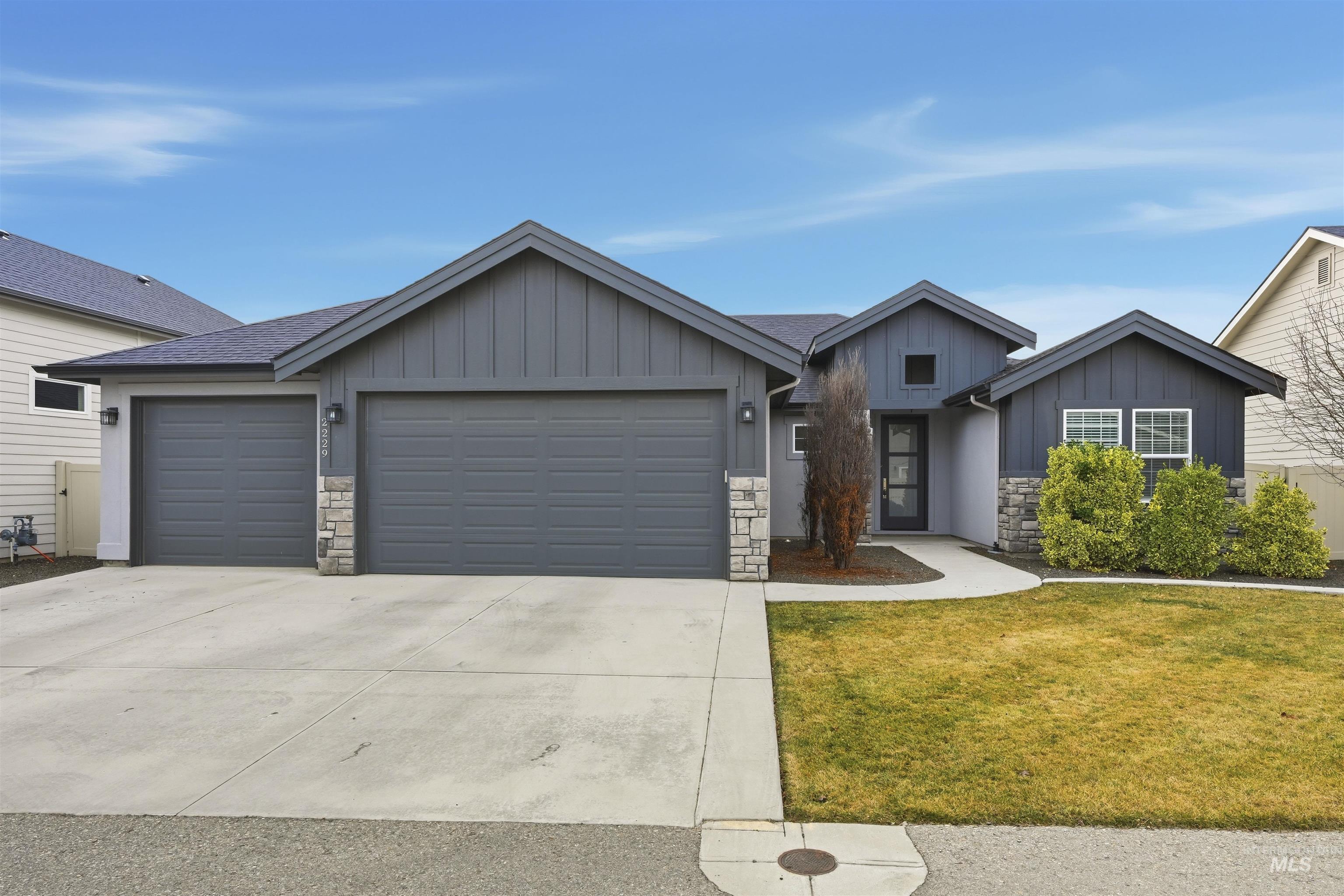 2229 East Grayson Street Meridian, ID 83642 - Photo 4 of 40 View of front of house featuring stone siding, board and batten siding, concrete driveway, a garage, and a front yard