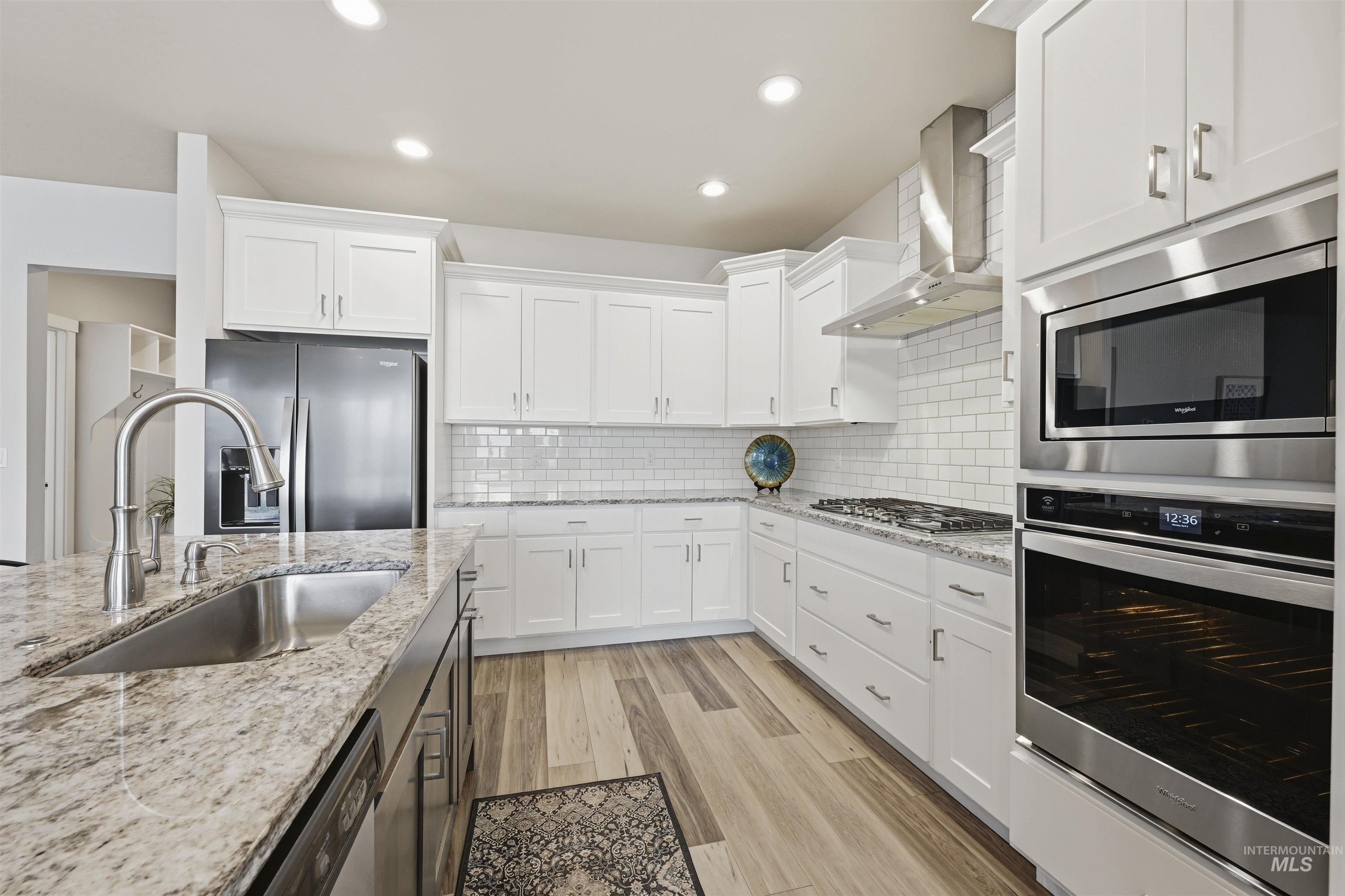 2229 East Grayson Street Meridian, ID 83642 - Photo 9 of 40 Kitchen featuring appliances with stainless steel finishes, white cabinetry, wall chimney exhaust hood, and recessed lighting