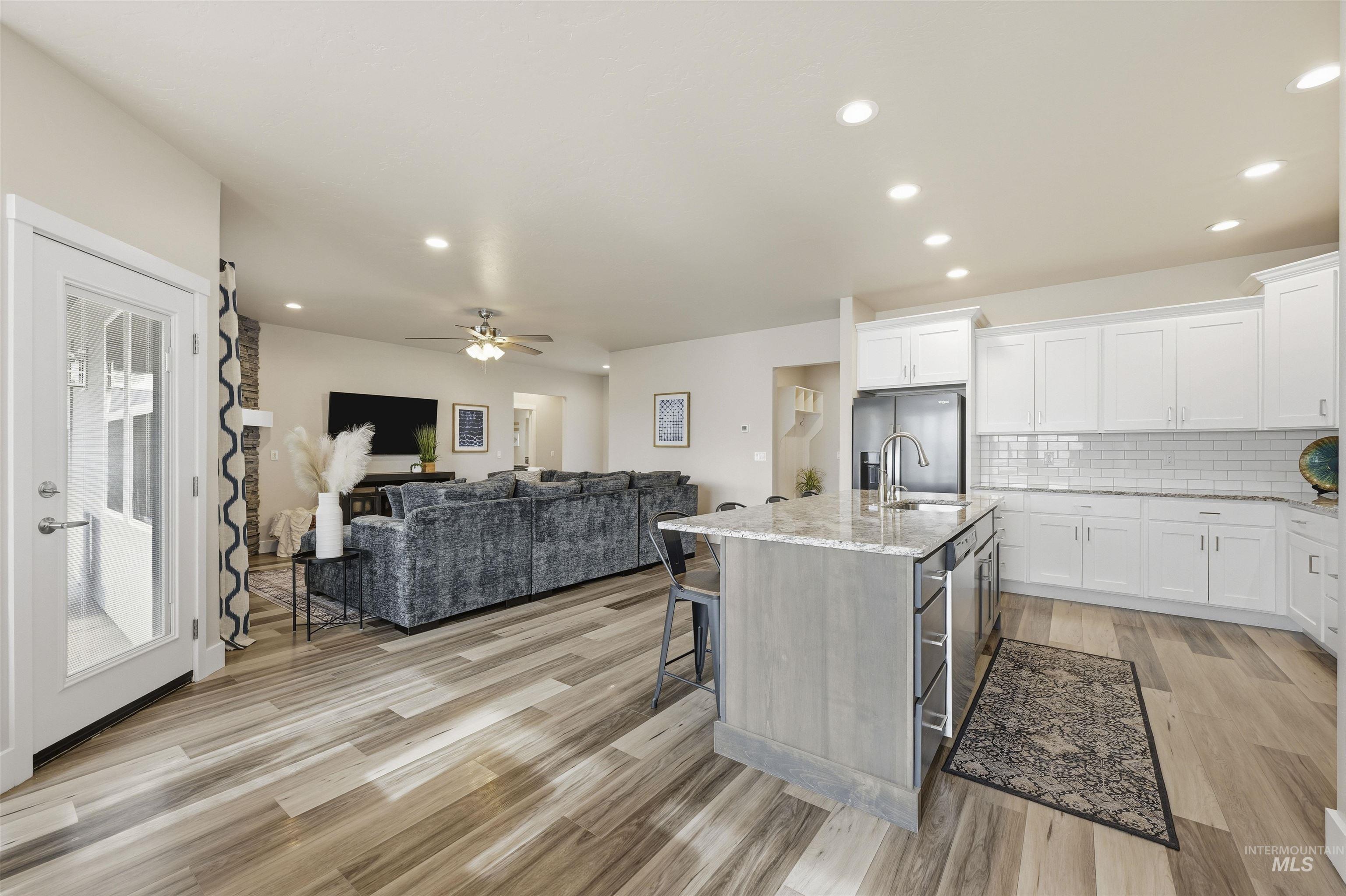 2229 East Grayson Street Meridian, ID 83642 - Photo 10 of 40 Kitchen with white cabinetry, a kitchen bar, an island with sink, light stone counters, and recessed lighting
