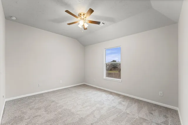 an empty room with a chandelier fan and window
