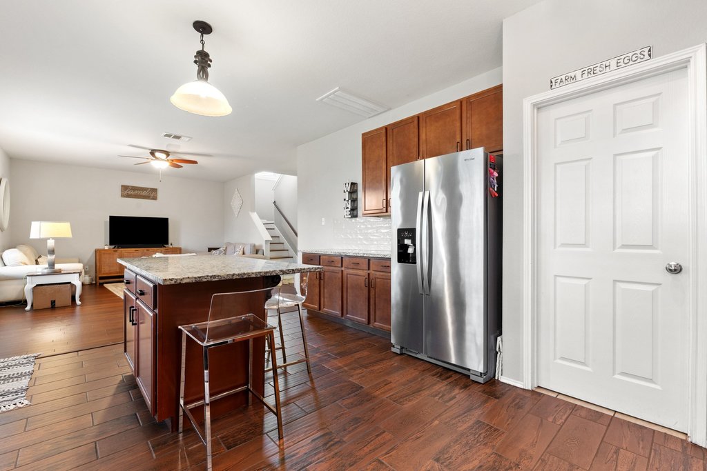 140 Wolfberry Path Buda, TX 78610 - Photo 15 of 35 a kitchen with stainless steel appliances kitchen island granite countertop a refrigerator a stove a sink a dining table and chairs with wooden floor
