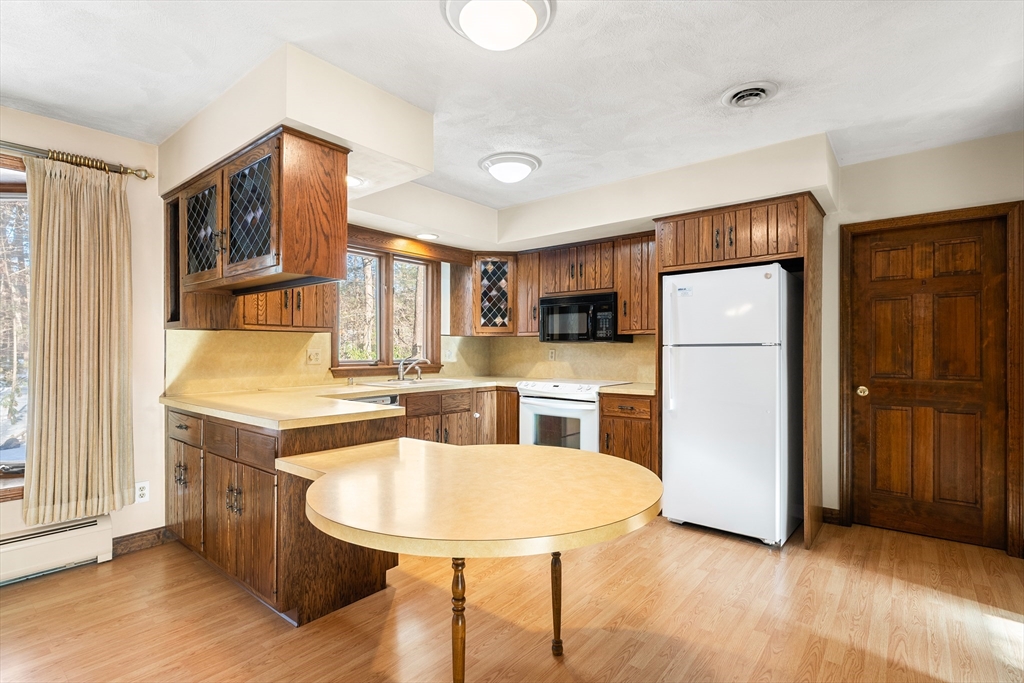 26 Nottingham Drive Raynham, MA 02767 - Photo 11 of 42 a kitchen with stainless steel appliances granite countertop a refrigerator a stove top oven a sink and a dining table with wooden floor