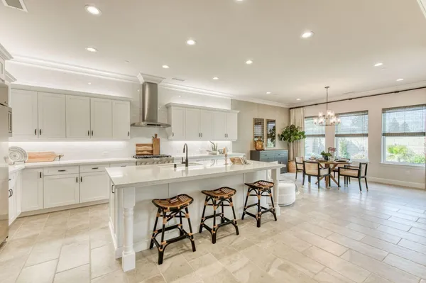 a kitchen with lots of white furniture a sink a stove and a dining table