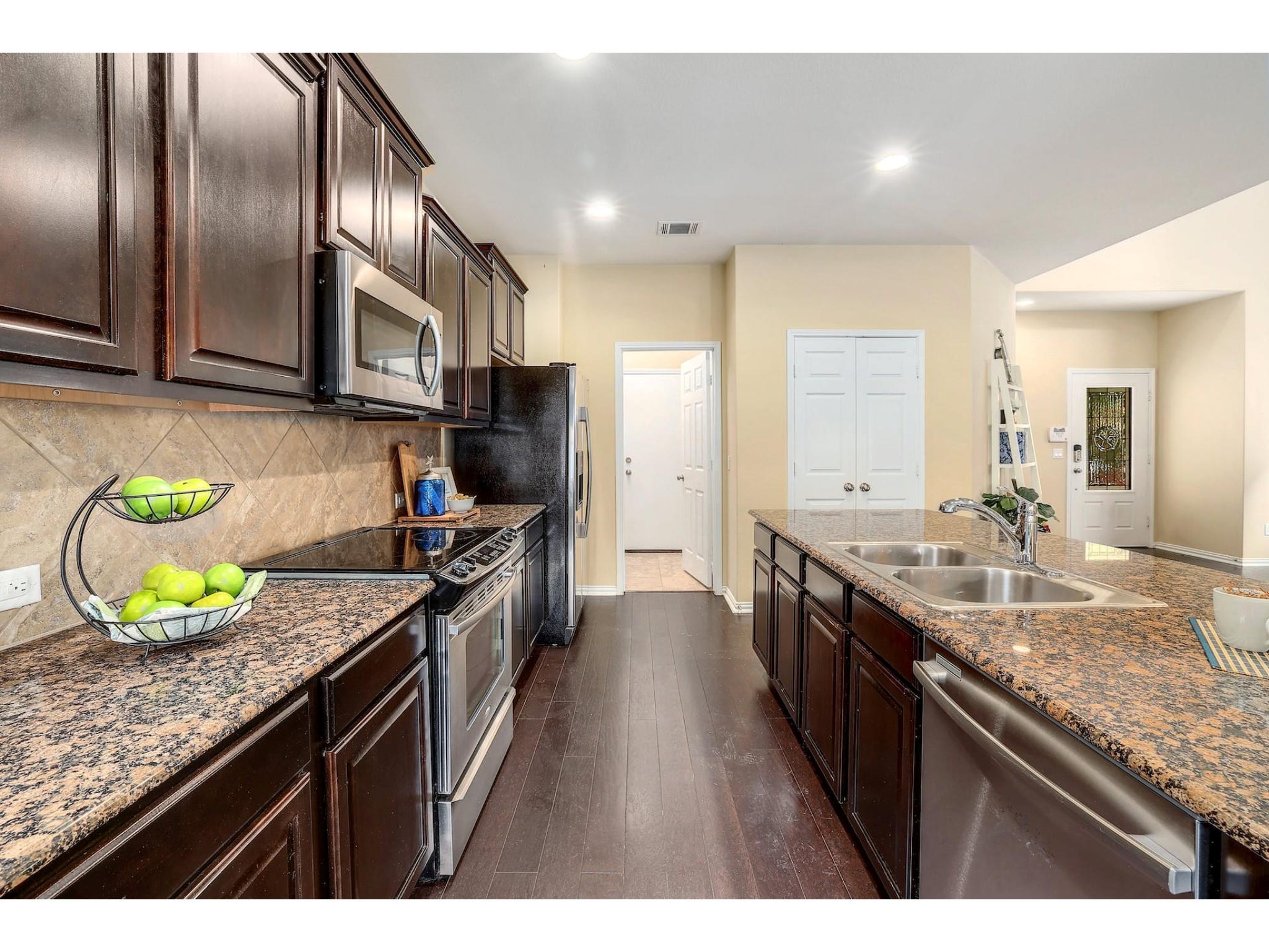 16021 Travesia Way Austin, TX 78728 - Photo 12 of 27 a kitchen with granite countertop stainless steel appliances a sink stove top oven and cabinets