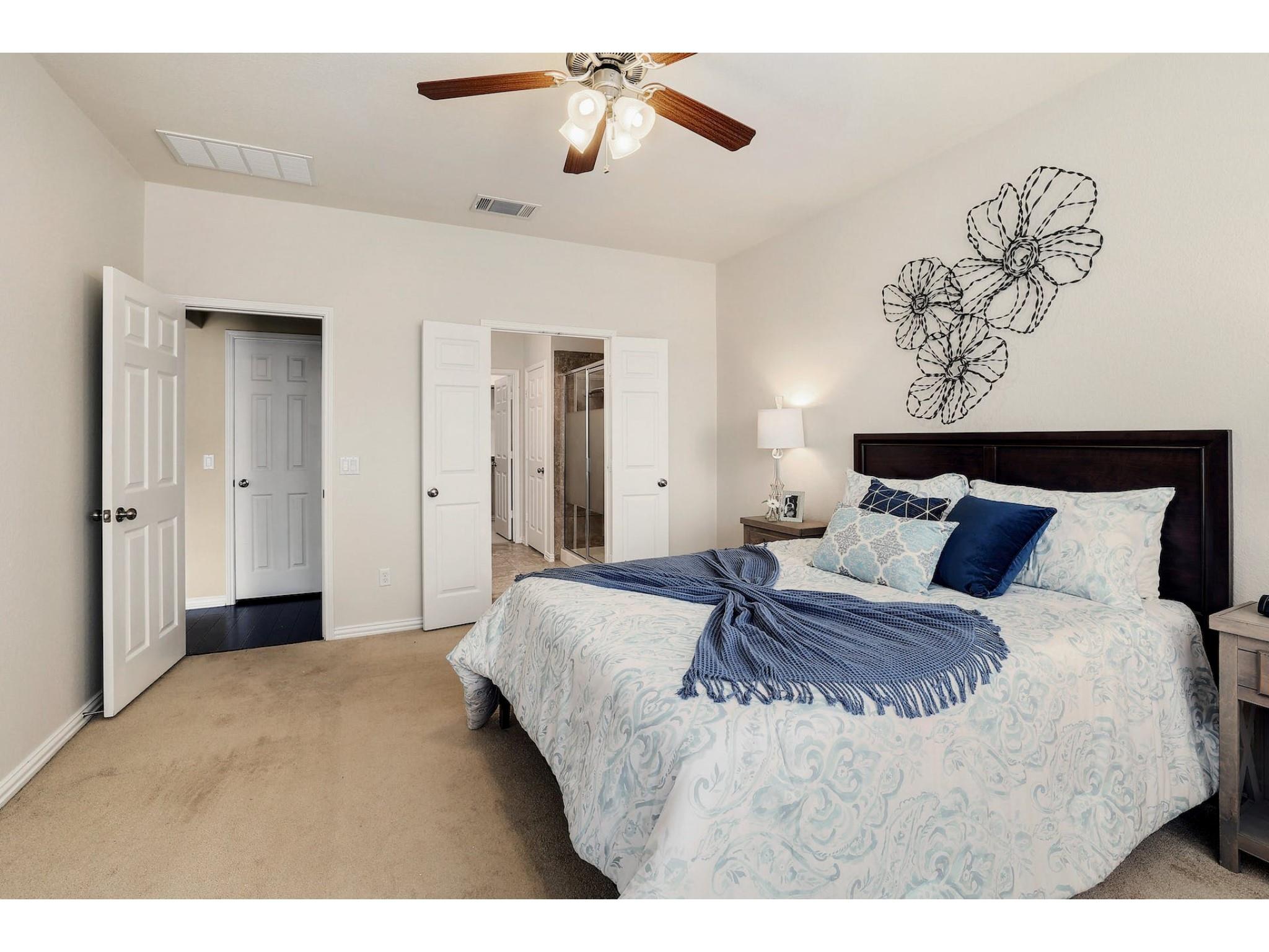 16021 Travesia Way Austin, TX 78728 - Photo 14 of 27 a bedroom with a large bed and a chandelier