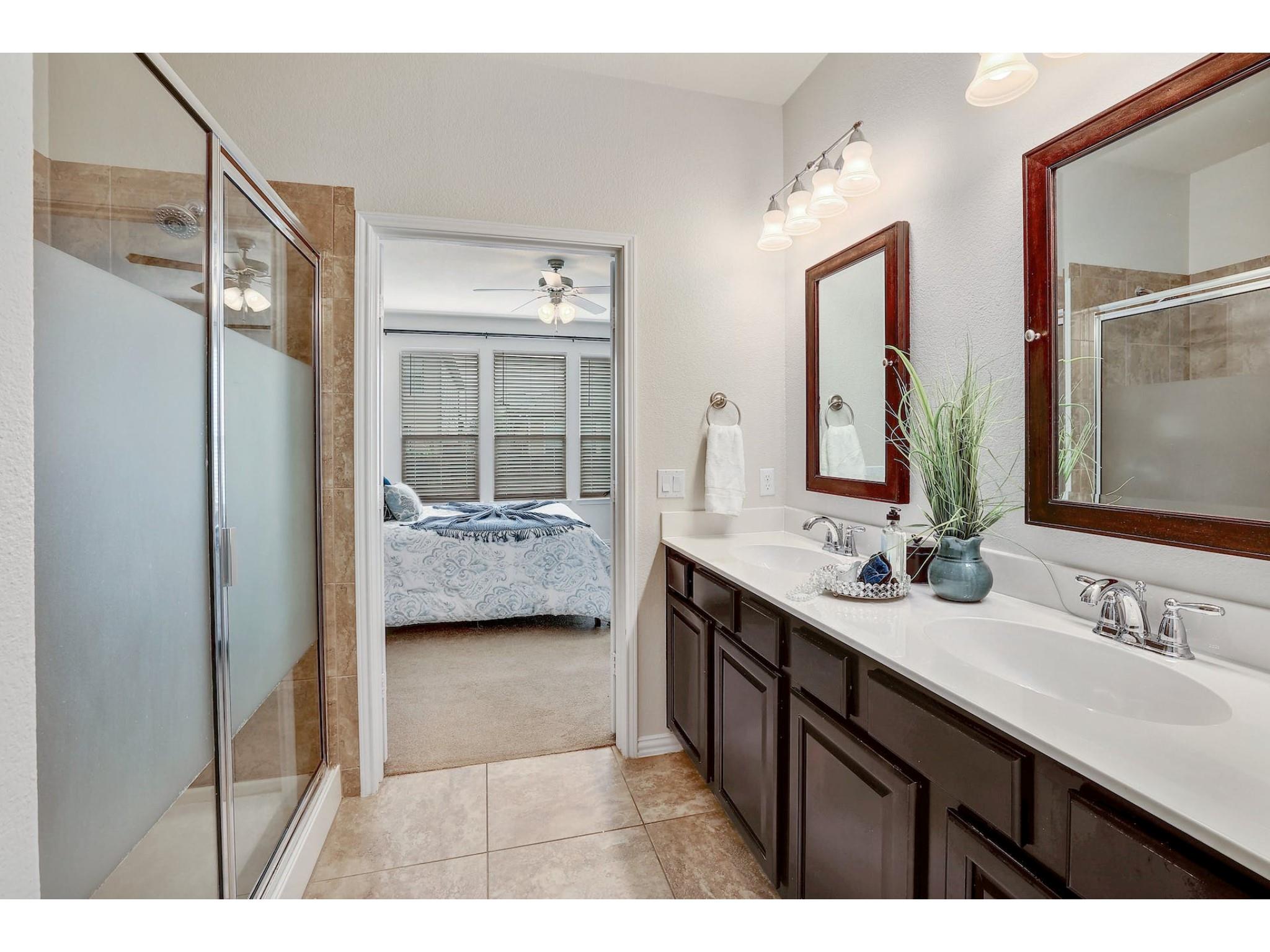 16021 Travesia Way Austin, TX 78728 - Photo 15 of 27 a en suite bathroom with a double vanity sink a mirror and a shower
