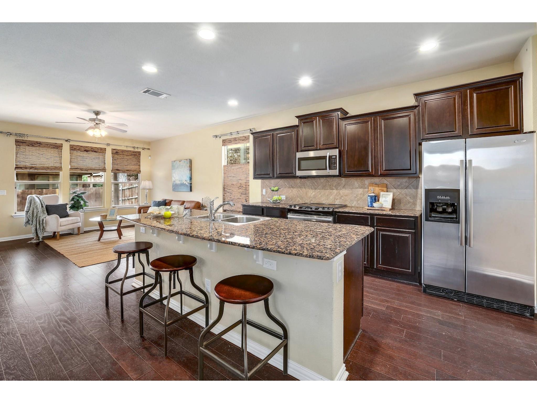 16021 Travesia Way Austin, TX 78728 - Photo 6 of 27 a kitchen with stainless steel appliances granite countertop a stove top oven a sink a refrigerator with a dining table and chairs
