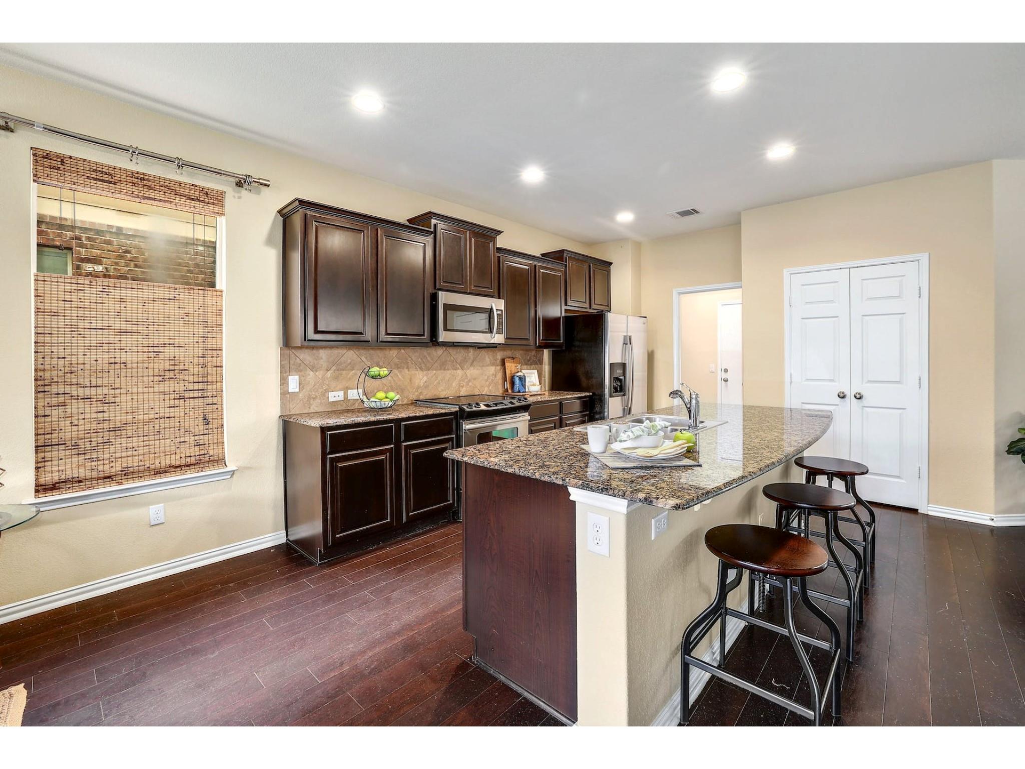 16021 Travesia Way Austin, TX 78728 - Photo 8 of 27 a kitchen with stainless steel appliances kitchen island granite countertop a stove top oven a sink and a refrigerator