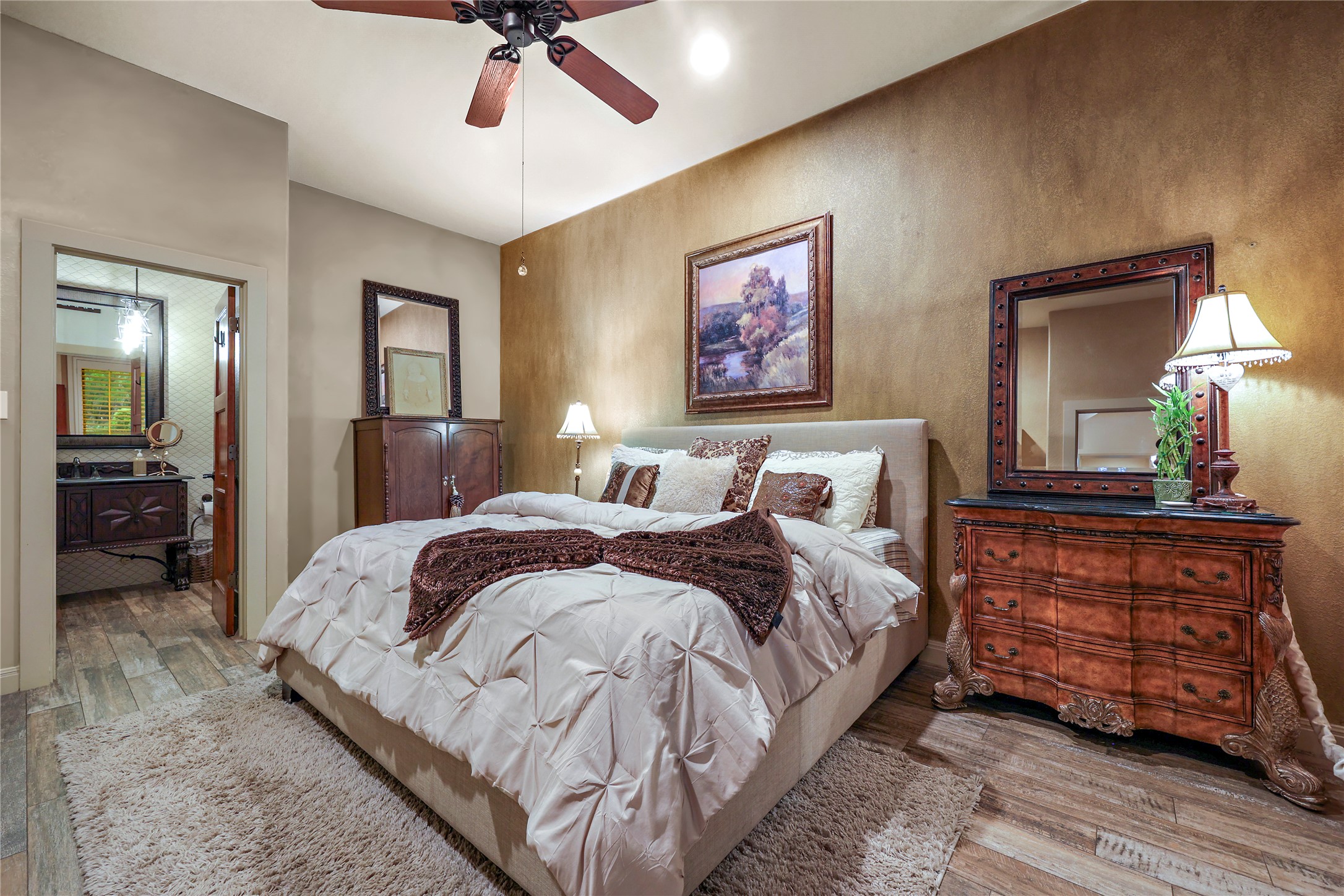 17501 Navigation Lane Lago Vista, TX 78645 - Photo 27 of 40 This downstairs bedroom features hardwood-style flooring, a ceiling fan, and direct access to a bathroom with a dark wood vanity