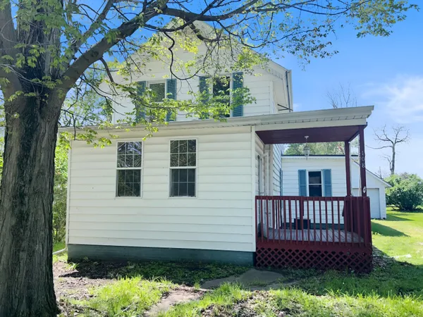 a view of a house with a small yard and a large tree