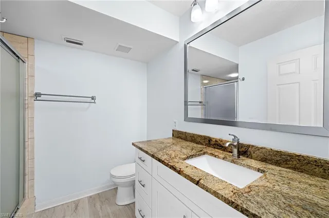 a bathroom with a granite countertop sink toilet and shower