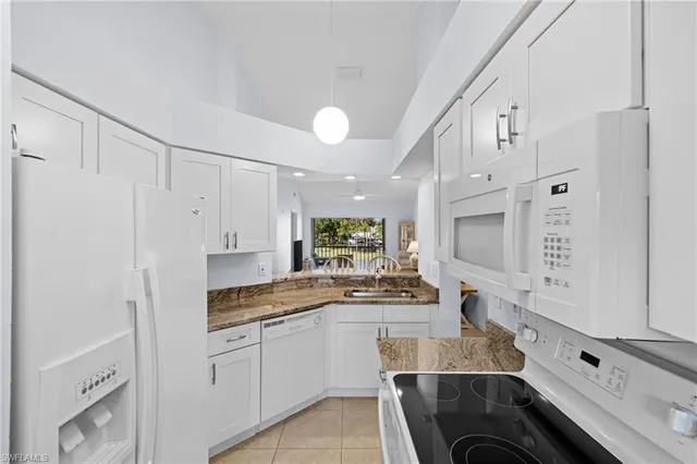 a kitchen with granite countertop white cabinets and white appliances