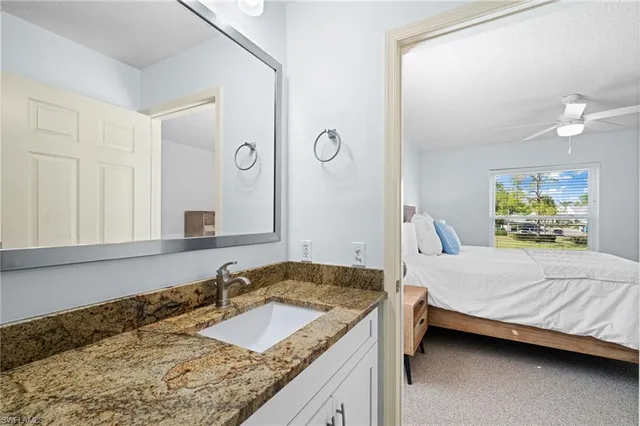 a bedroom with a granite countertop sink and a mirror