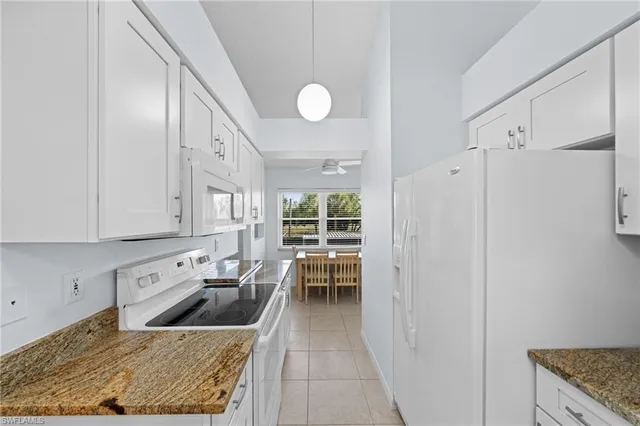 a kitchen with granite countertop a stove a sink and a refrigerator
