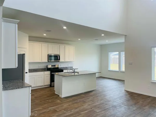 a kitchen with stainless steel appliances a stove top oven a sink a refrigerator and cabinets