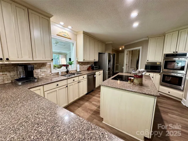 a kitchen with stainless steel appliances granite countertop a sink stove refrigerator and cabinets