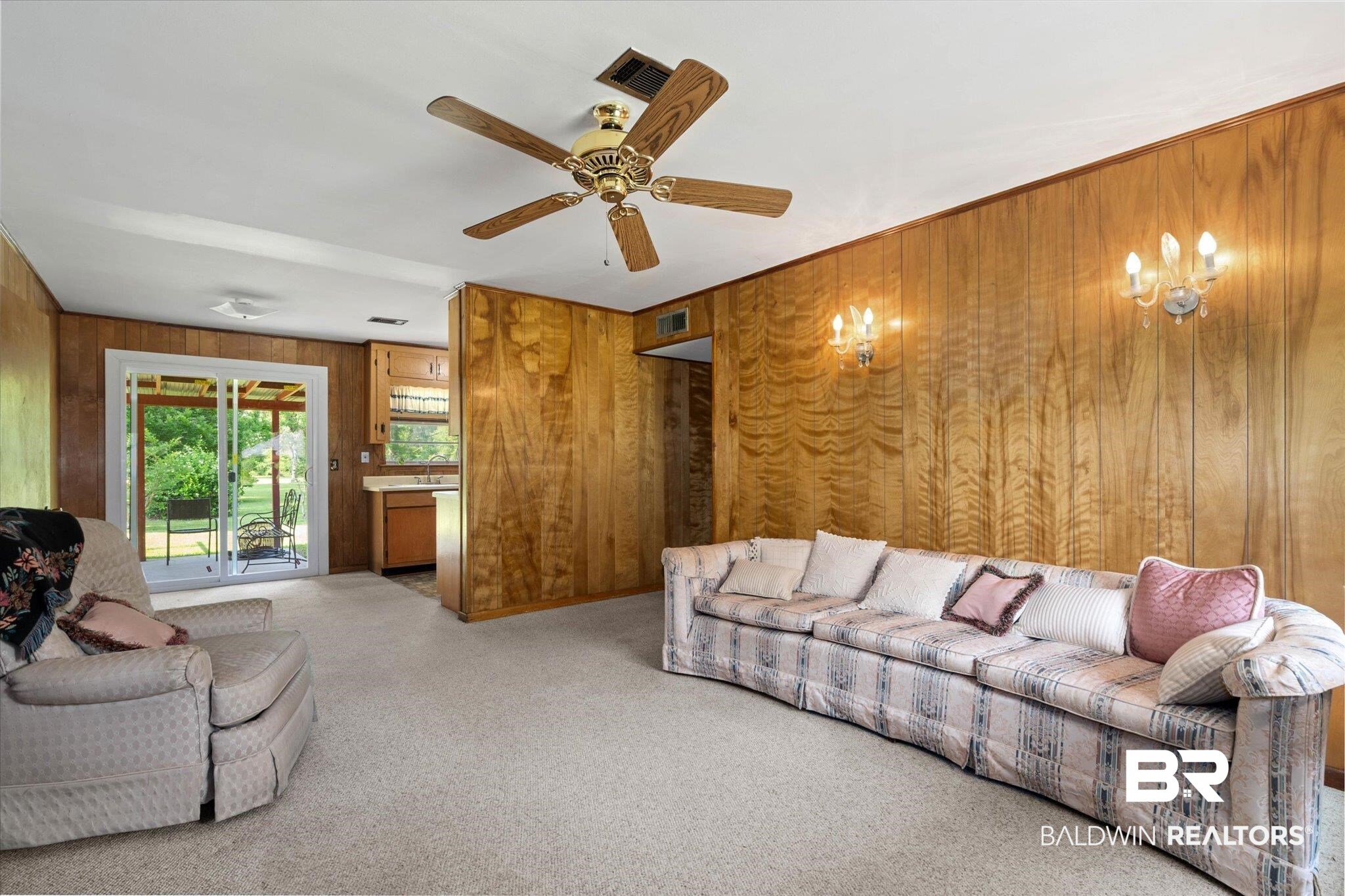423 First Avenue Saraland, AL 36571 - Photo 2 of 20 Carpeted living room with wooden walls, a chandelier, and a ceiling fan