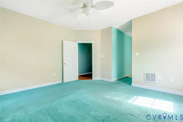 a view of an empty room with window and chandelier fan