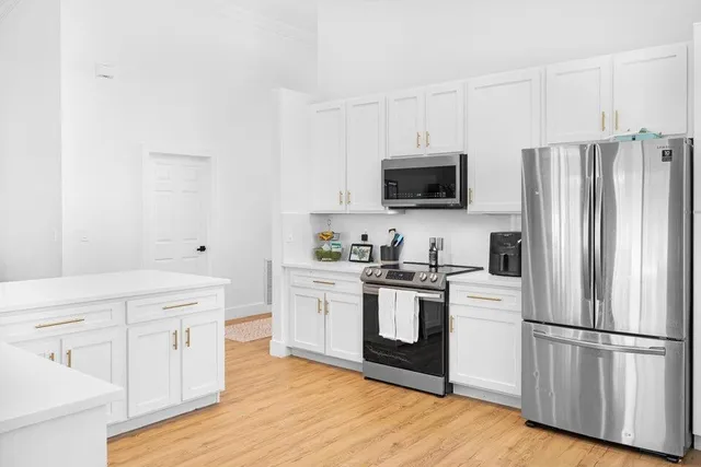 a kitchen with white cabinets white stainless steel appliances and wooden floors