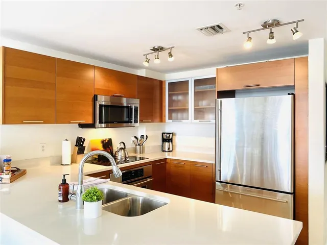 a kitchen with stainless steel appliances granite countertop a sink and a refrigerator