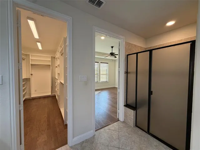a view of a hallway with wooden floor and a bathroom