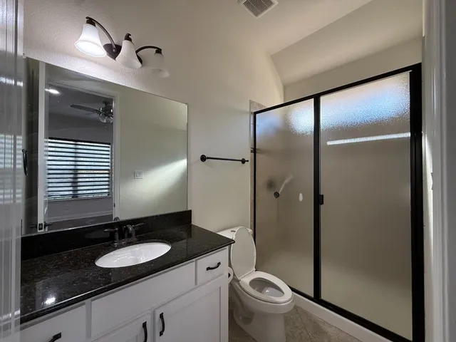 a bathroom with a granite countertop sink toilet and a mirror