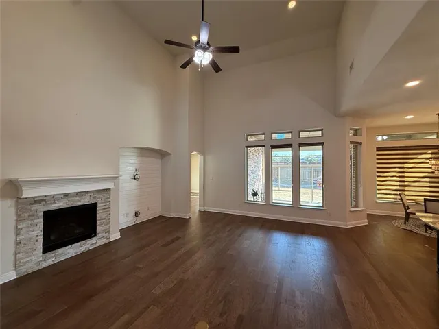 an empty room with wooden floor fireplace and windows