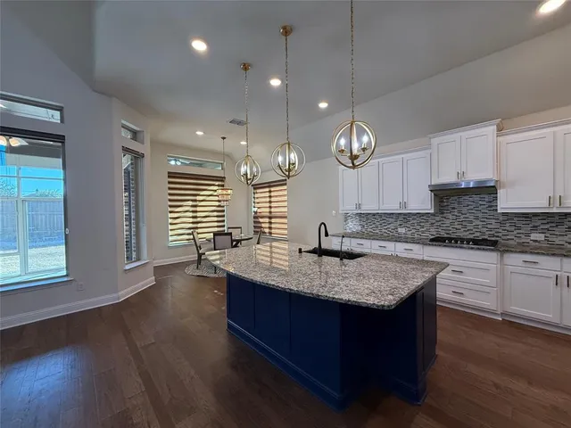 a kitchen with granite countertop a stove a sink and a wooden floor