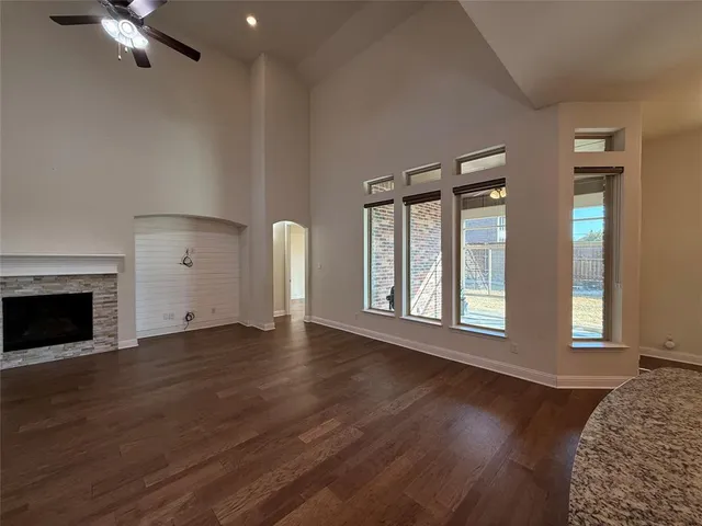a view of an empty room with wooden floor fireplace and a window