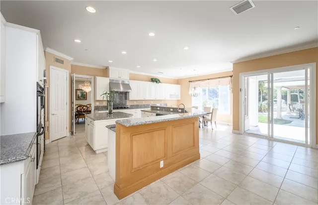a dining room with stainless steel appliances kitchen island granite countertop a table chairs and a kitchen view
