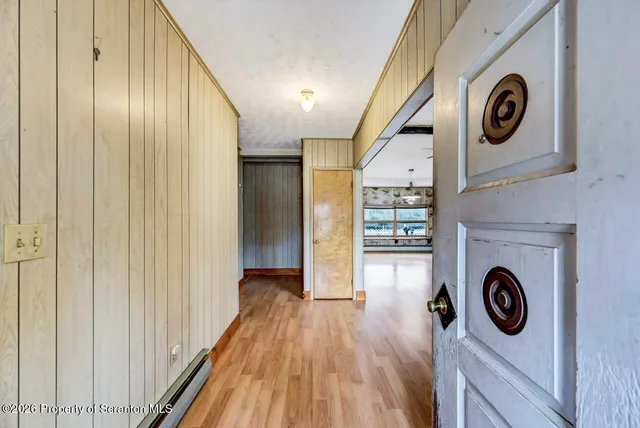 a view of an empty room with a window and wooden floor