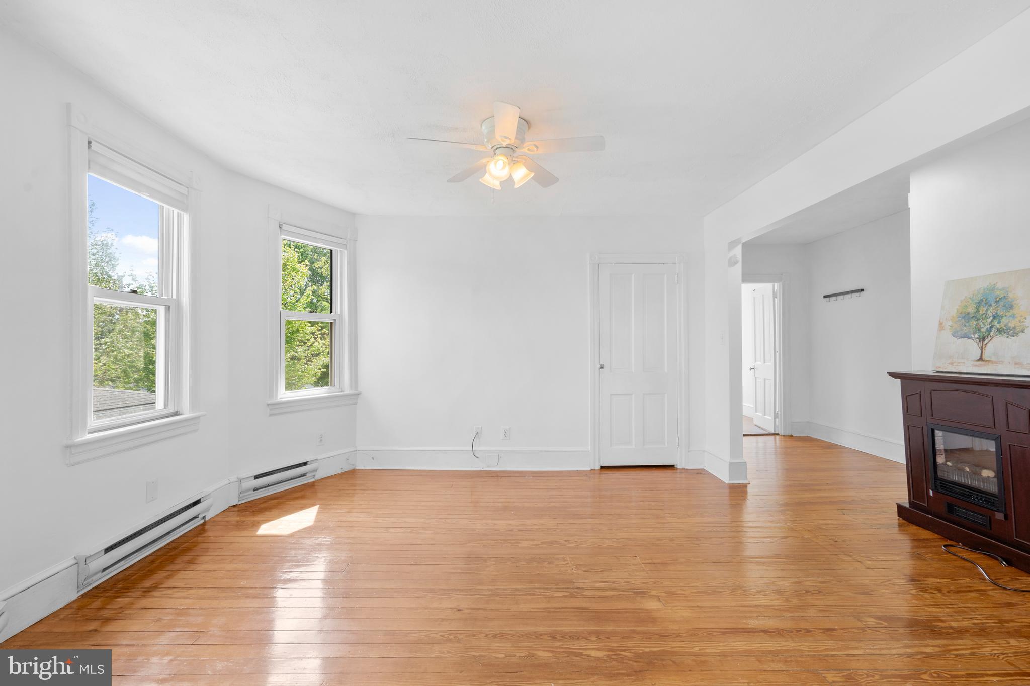 an empty room with wooden floor fan and windows