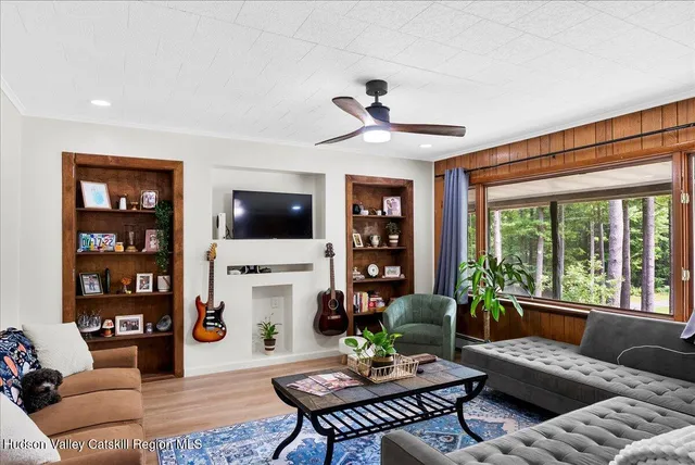 a living room with furniture a flat screen tv and a large window