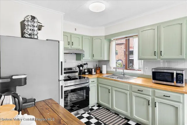 a kitchen with stainless steel appliances a stove a sink cabinets and a window