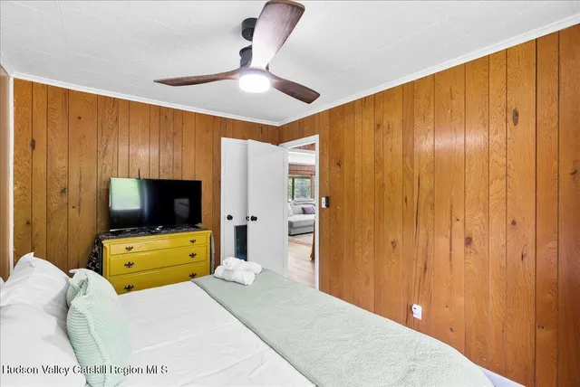 a bedroom with a bed and a flat tv screen on dresser