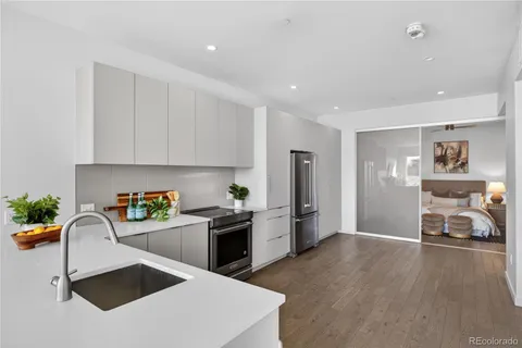 a kitchen with stainless steel appliances granite countertop a refrigerator a sink a stove and white cabinets