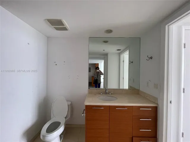 a bathroom with a granite countertop sink a toilet and mirror