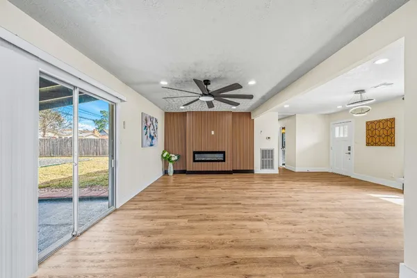 a view of empty room with wooden floor and fan