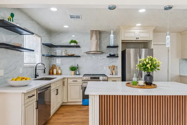 a kitchen with stainless steel appliances granite countertop a sink a refrigerator and a stove