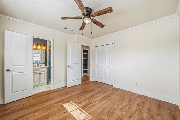 a view of empty room with wooden floor and ceiling fan