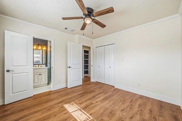 a view of empty room with wooden floor and ceiling fan