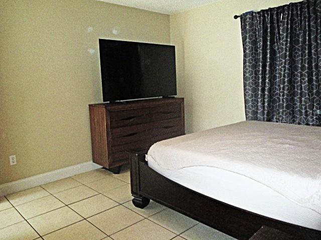 12932 81st Avenue Seminole, FL 33776 - Photo 9 of 27 a bedroom with a bed and a flat tv screen on dresser