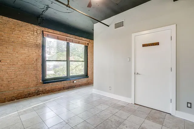 a view of an empty room with window and chandelier fan