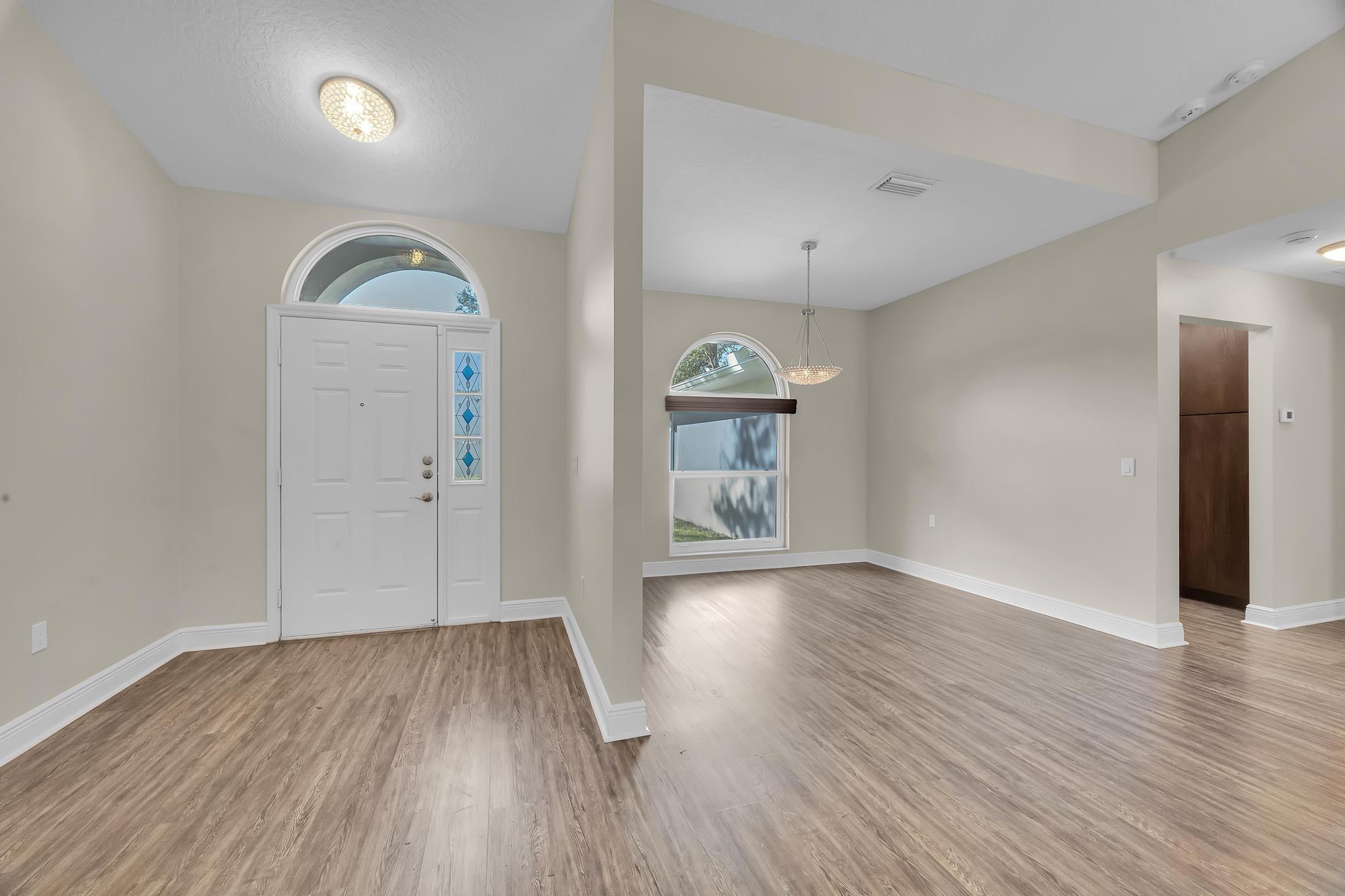 8330 Hidden Pines Road Fort Pierce, FL 34945 - Photo 11 of 34 an empty room with wooden floor and mirror