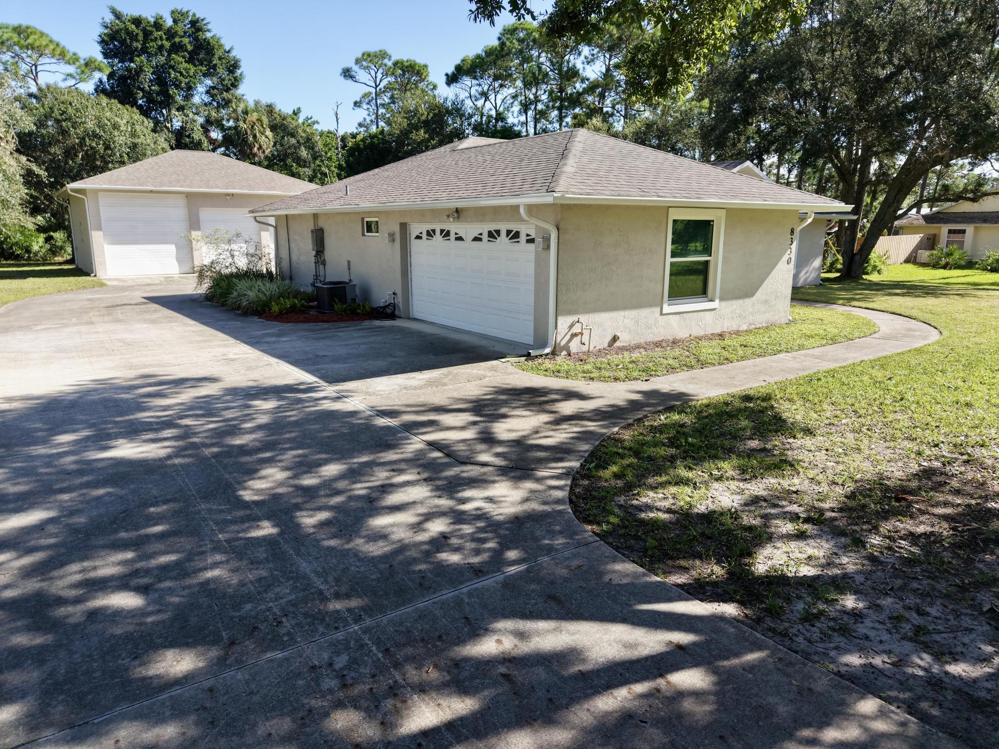 8330 Hidden Pines Road Fort Pierce, FL 34945 - Photo 4 of 34 a view of a white house with a yard and large trees